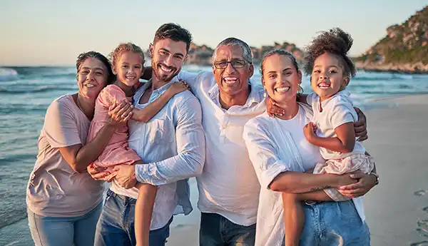 A group photo of a family smiling on a beach