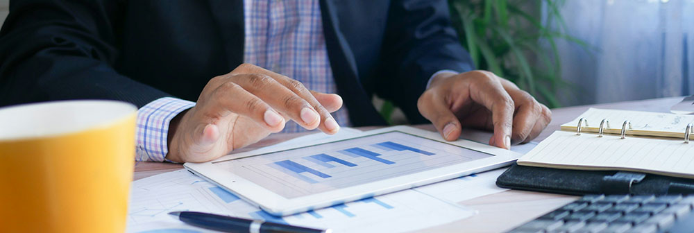 a man using a tablet displaying graphs