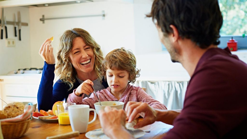 A family laughing together over breakfast at the kitchen table