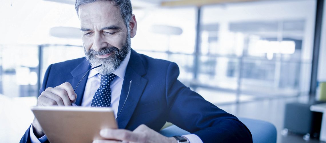 Elegant business multitasking multimedia man using devices at office