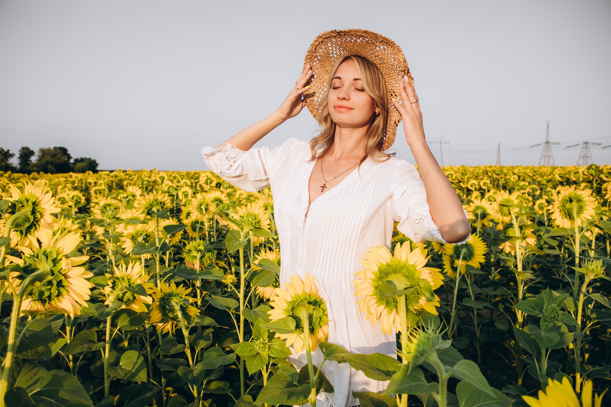 Girl in a straw hat and a sundress in a field of sunflowers