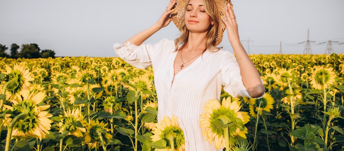 Girl in a straw hat and a sundress in a field of sunflowers