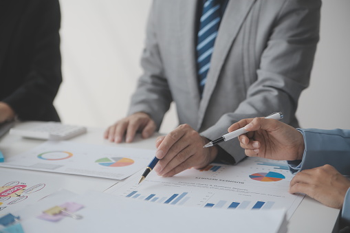 Financial analysts analyze business financial reports on a digital tablet planning investment project during a discussion at a meeting of corporate showing the results of their successful teamwork.