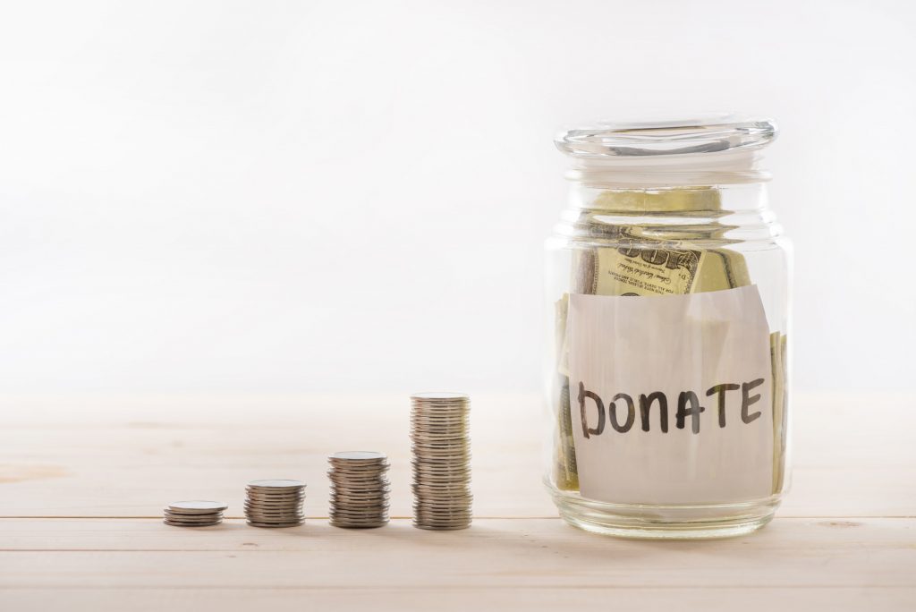 Close-up view of dollar banknotes in glass jar and stacked coins, donation concept