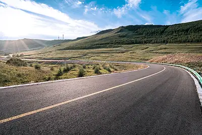 a long road with a bright sun